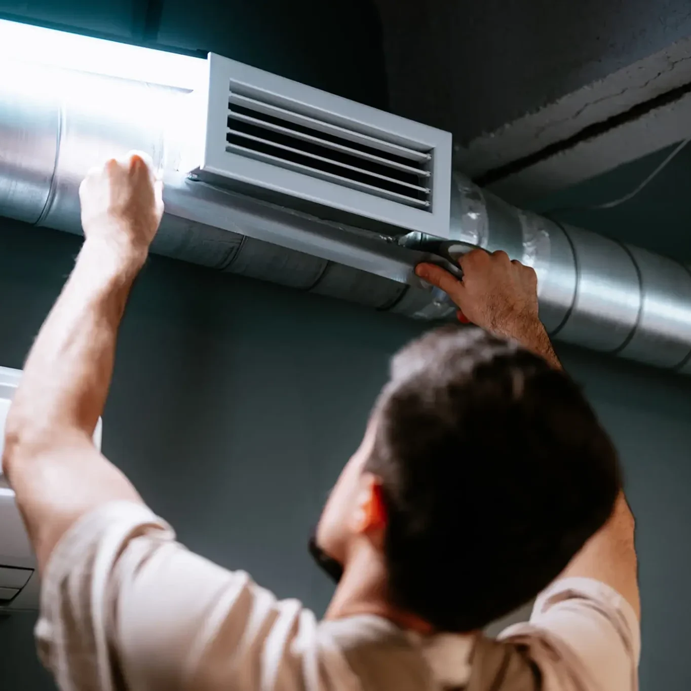 Man adjusting air vent on ceiling. Man adjusting air vent on ceiling.