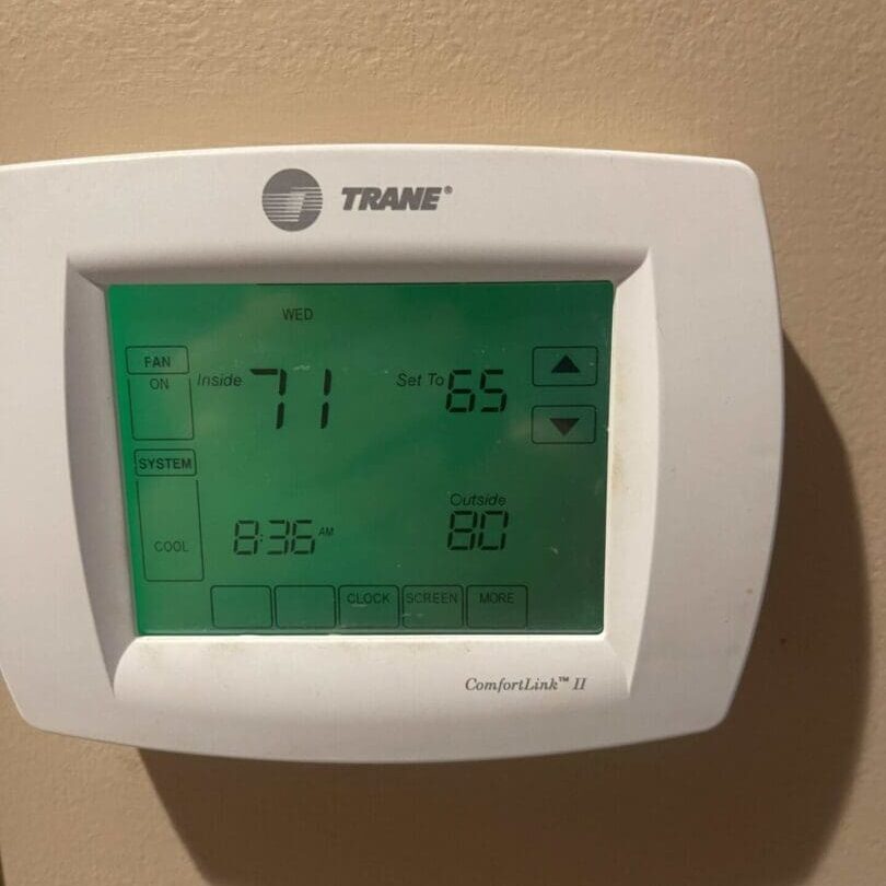 A digital thermostat is shown on the wall.